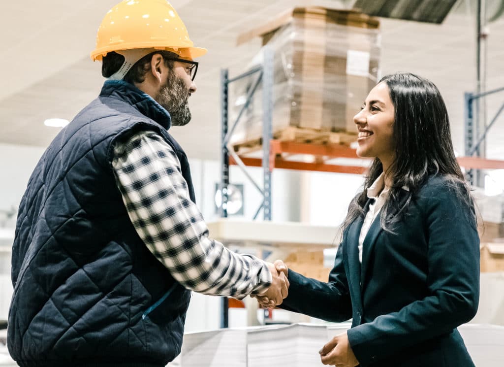 Smiling office manager shaking hands with factory worker