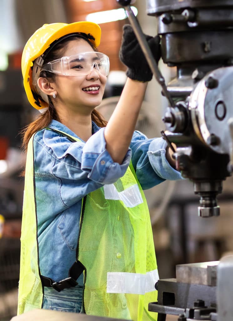 Woman worker wearing safety goggles control lathe machine